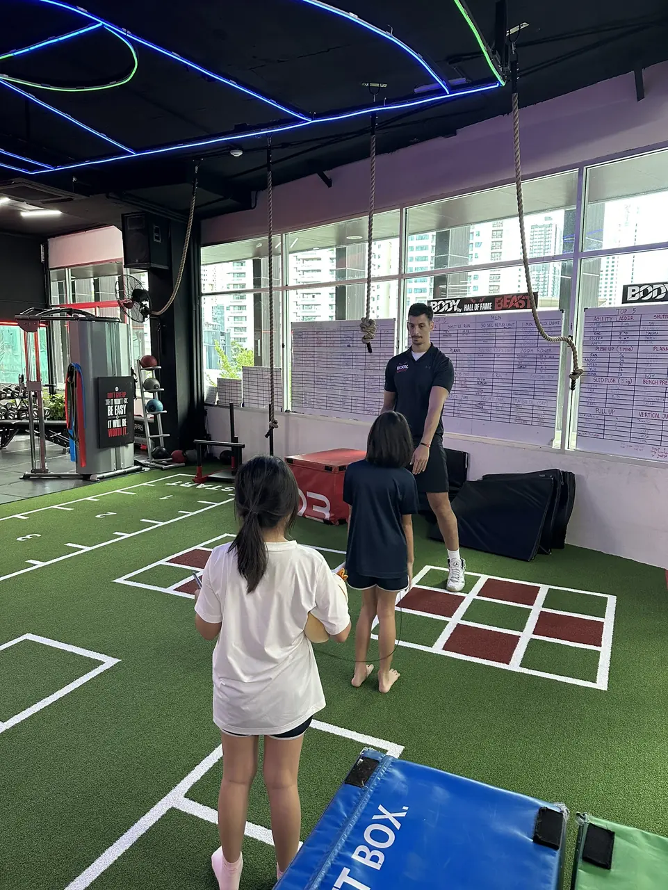 Coach briefing two young girls before an agility drill at Body By Beast Underdogs, Bangkok