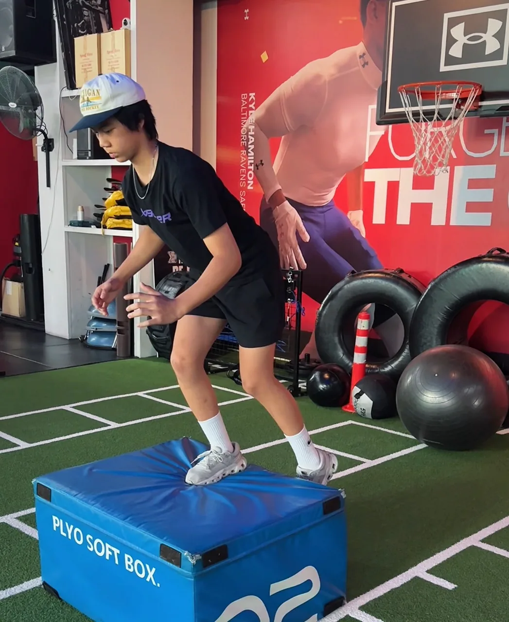 Teen athlete practising a controlled plyometric box landing during youth athletic training in Bangkok